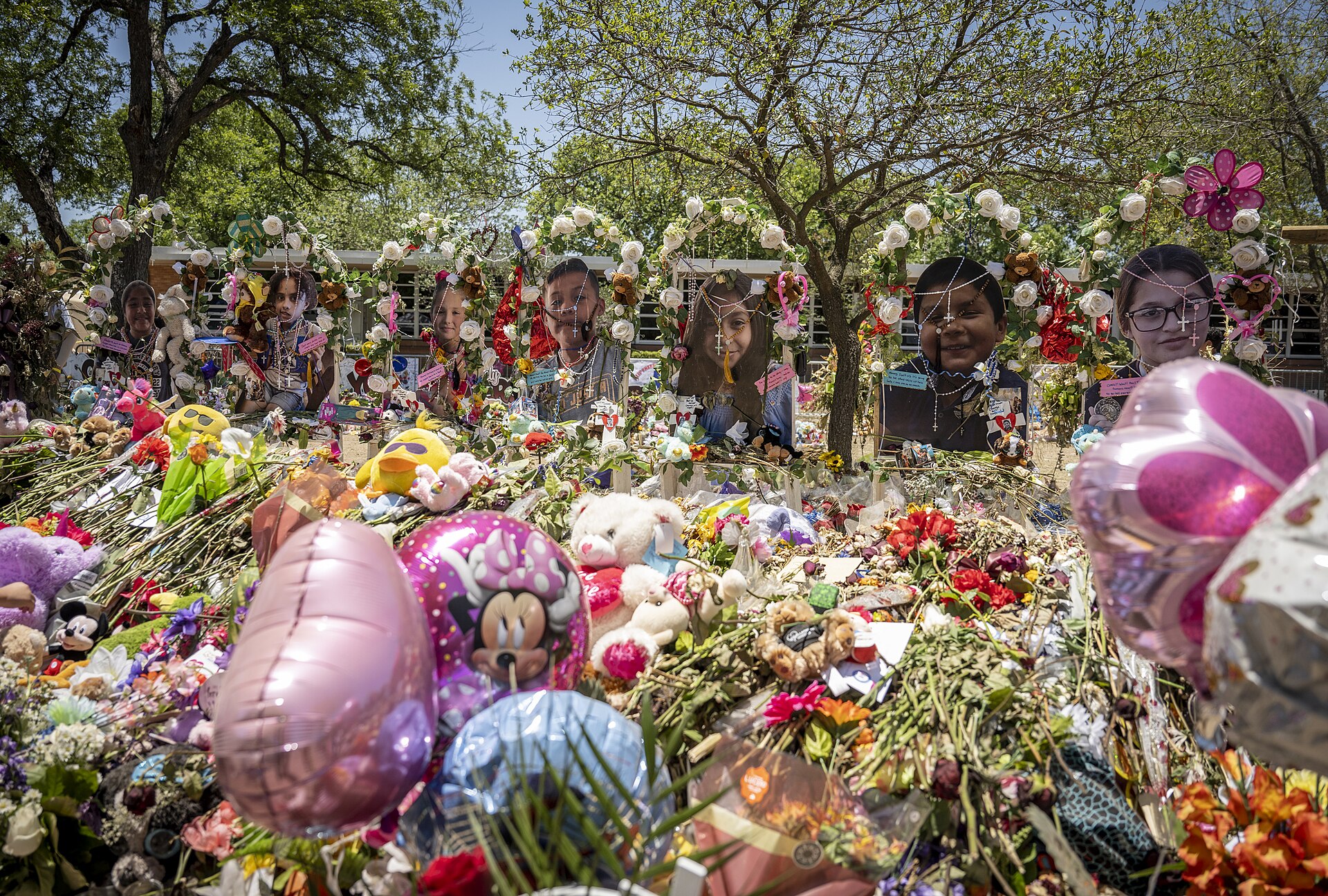 Flowers, toys, balloons, and portrait tributes at the Robb Elementary School memorial site in June 2022